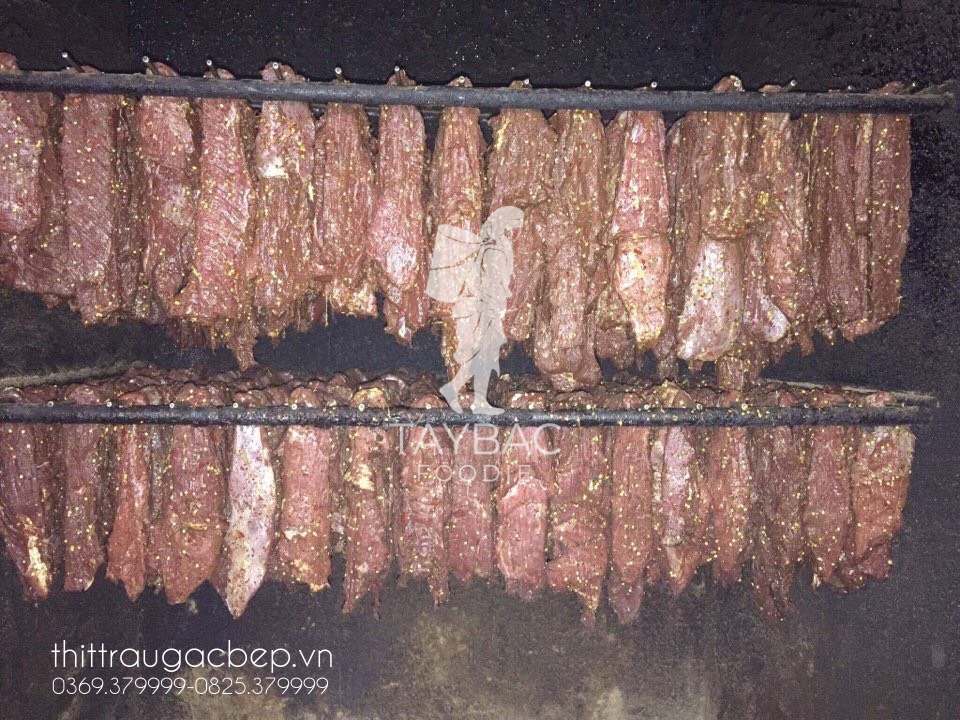 Công việc sấy thịt trâu thủ công bằng củi, mía và ngải cứu, không dùng lò sấy điện.